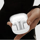 White wireless earbuds in a charging case held by a person against a neutral background