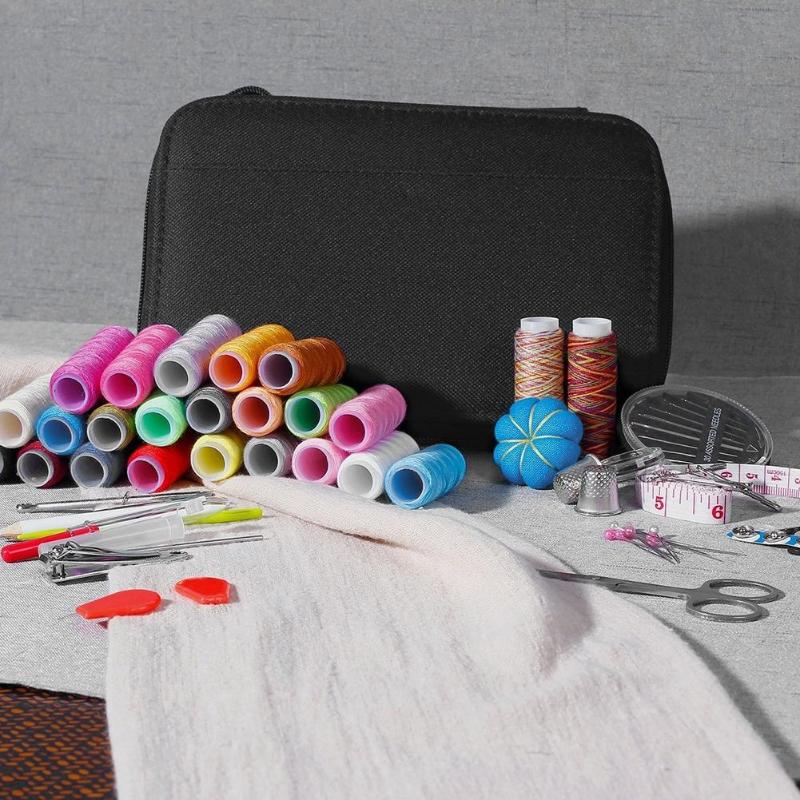 Collection of sewing supplies including spools of thread, scissors, and a black case on a gray surface.