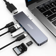 Cable organizer with USB hub, cables, and memory card in front of a laptop.