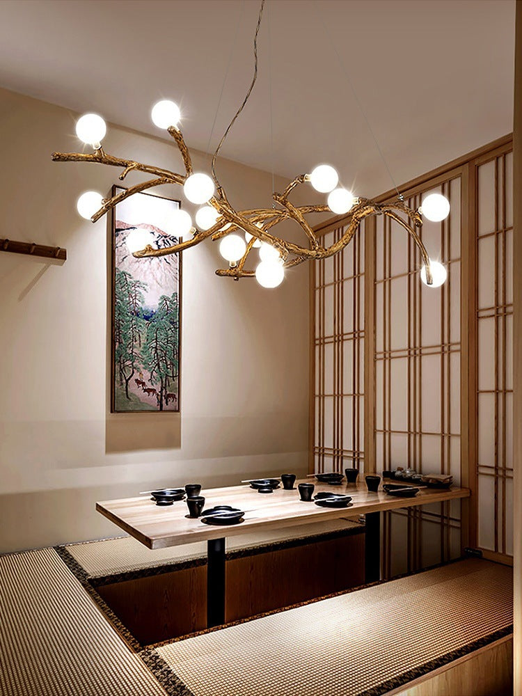 Modern interior design with a chandelier resembling branches, a dining table, and a wall painting.
