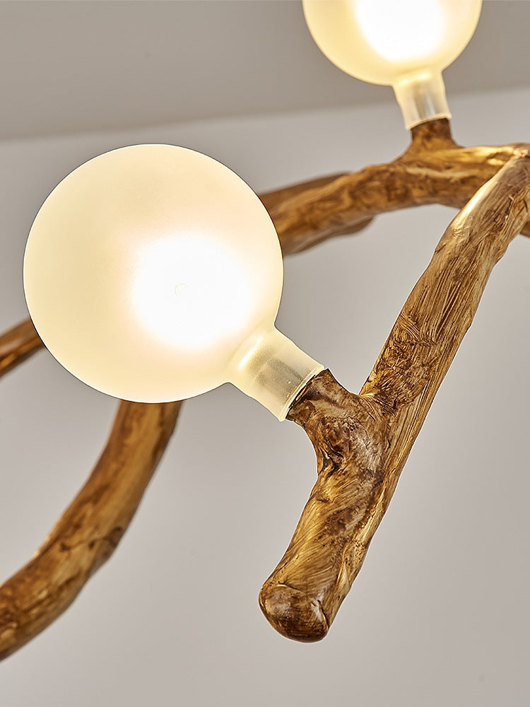 Light fixture with wooden branches and spherical bulbs on a neutral background