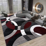 Living room with a geometric patterned rug, gray sectional sofa, and modern decor.