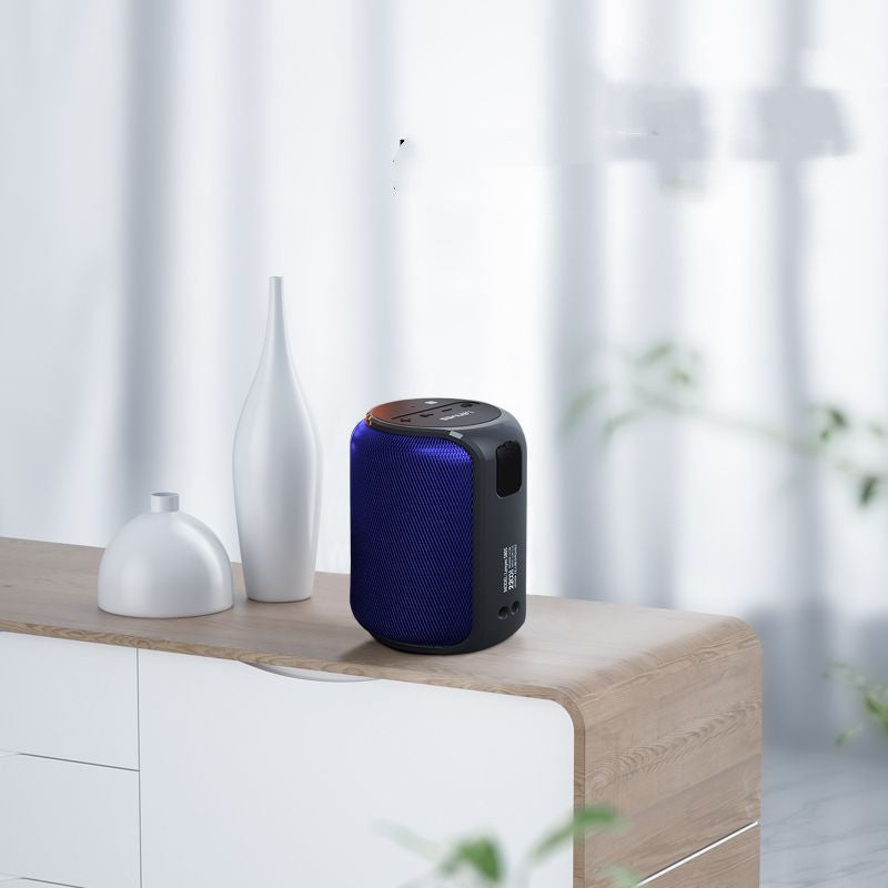 Blue and black portable speaker on a wooden surface with white vases and a blurred background