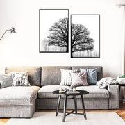 Living room with a gray sectional sofa, decorative pillows, and two framed black and white tree prints on the wall.