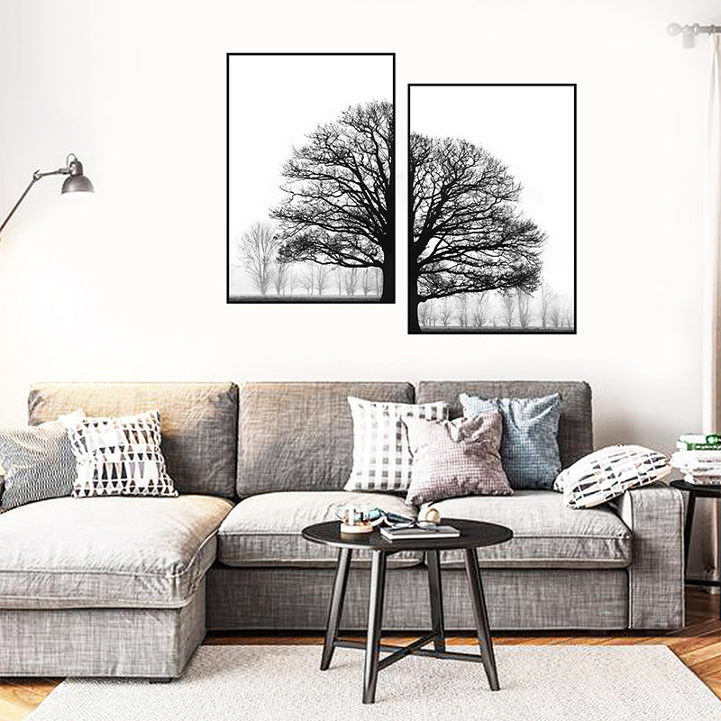 Living room with a gray sectional sofa, decorative pillows, and two framed black and white tree prints on the wall.