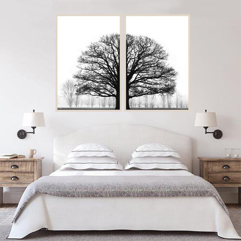 Two framed black and white tree prints above a bed in a bedroom setting.