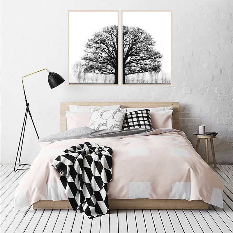 Bedroom with a bed, lamp, and wall art of trees.