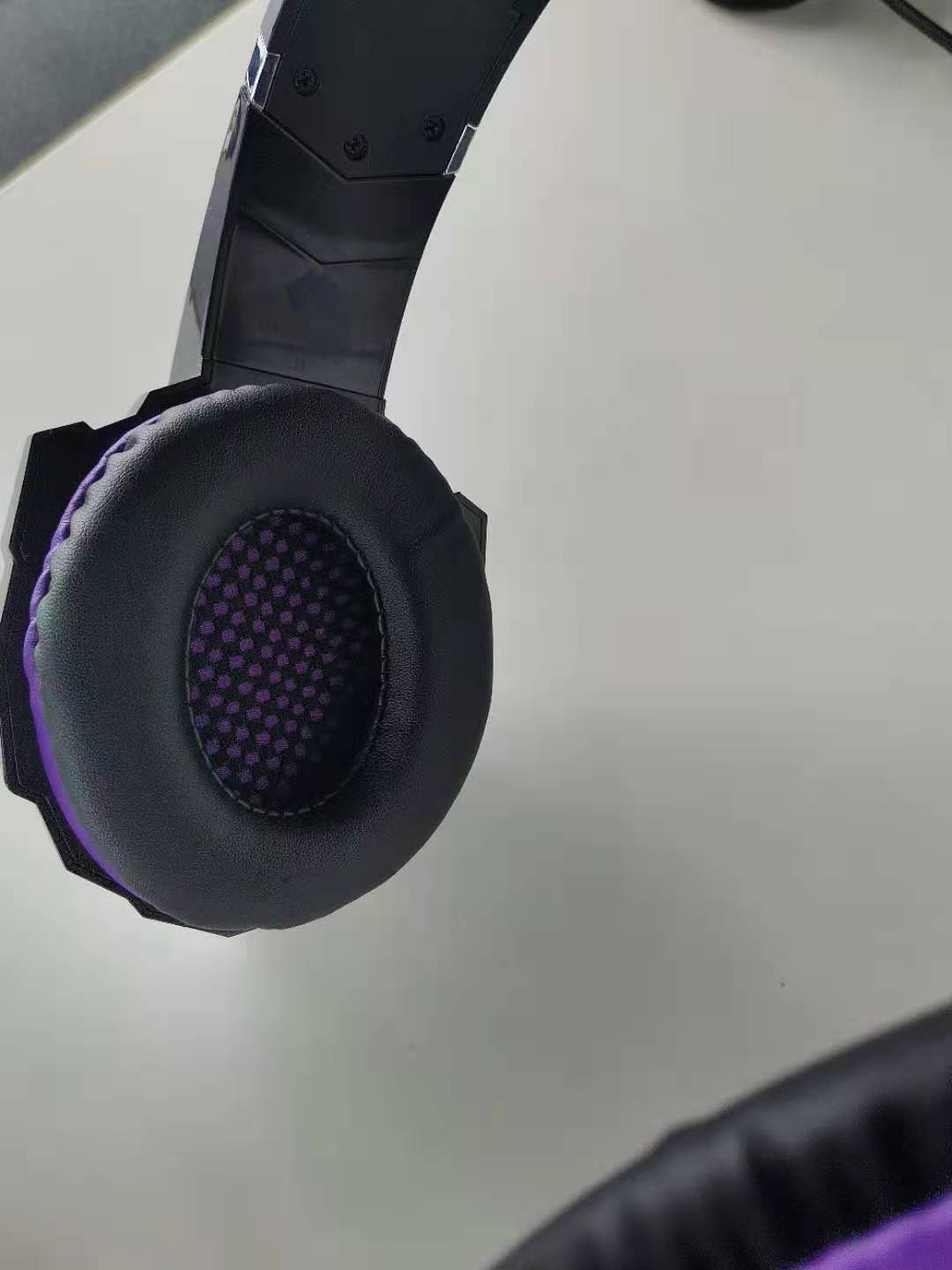 Close-up of a black and purple gaming headset on a white surface