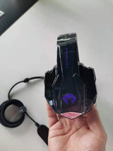 Gaming headset with cable held in a hand on a white surface