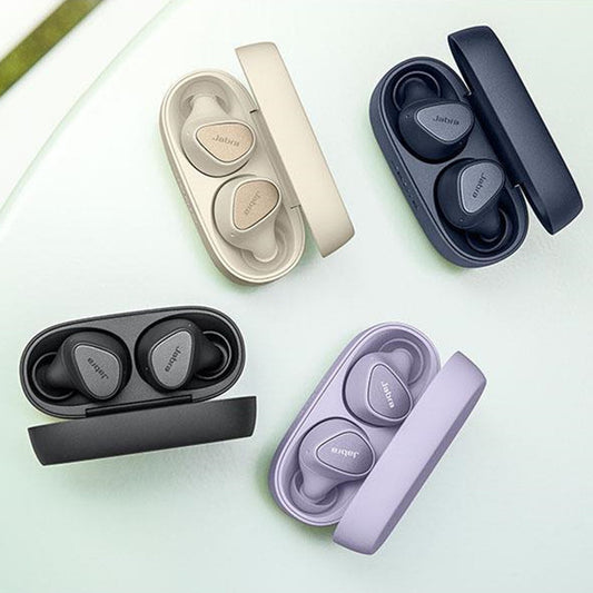 Set of wireless earbuds in various colors with their charging cases on a light green background.