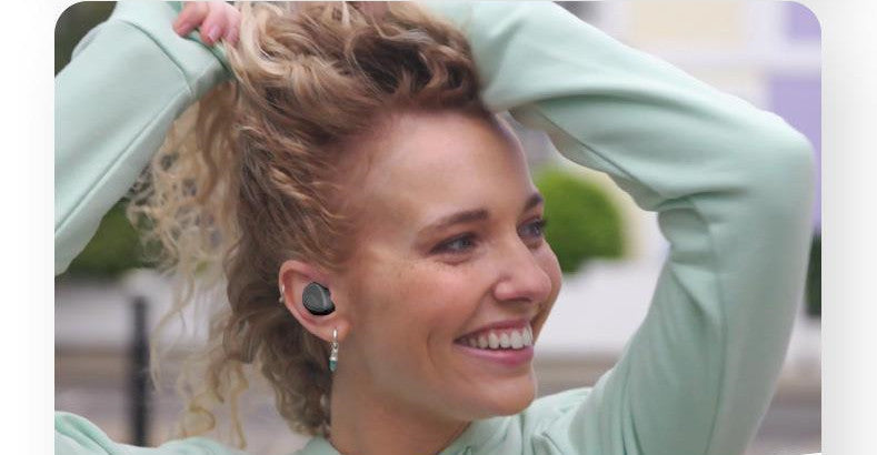 Woman wearing wireless earbuds with a blurred outdoor background