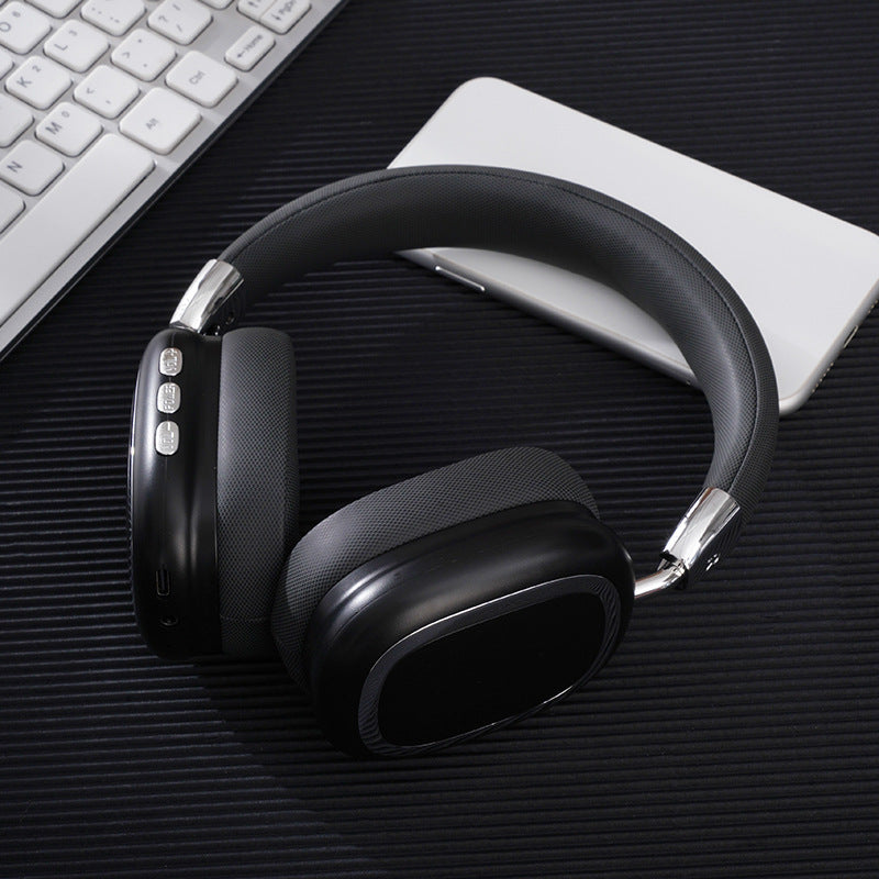 Black over-ear headphones on a dark surface with a keyboard and notebook in the background