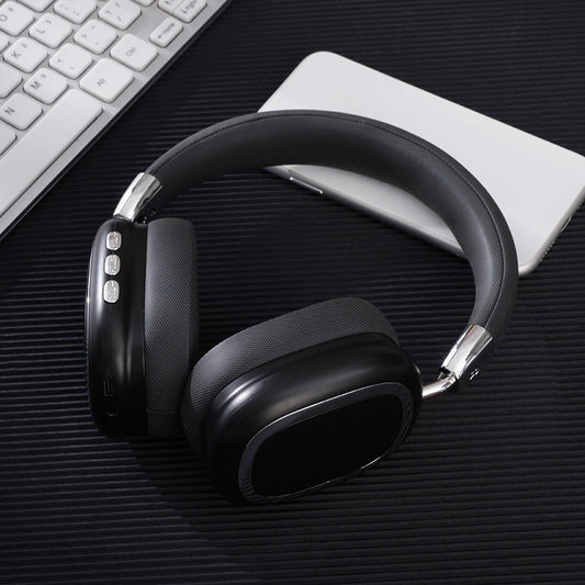 Black over-ear headphones on a dark surface with a keyboard and notebook in the background