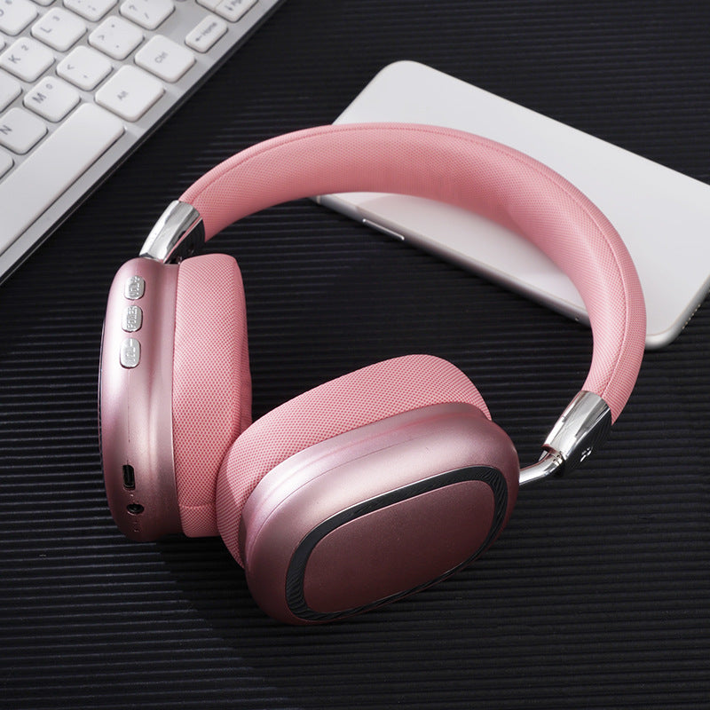 Pink headphones on a dark surface with a keyboard and mouse in the background