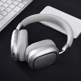 White headphones on a dark surface with a keyboard and white device in the background