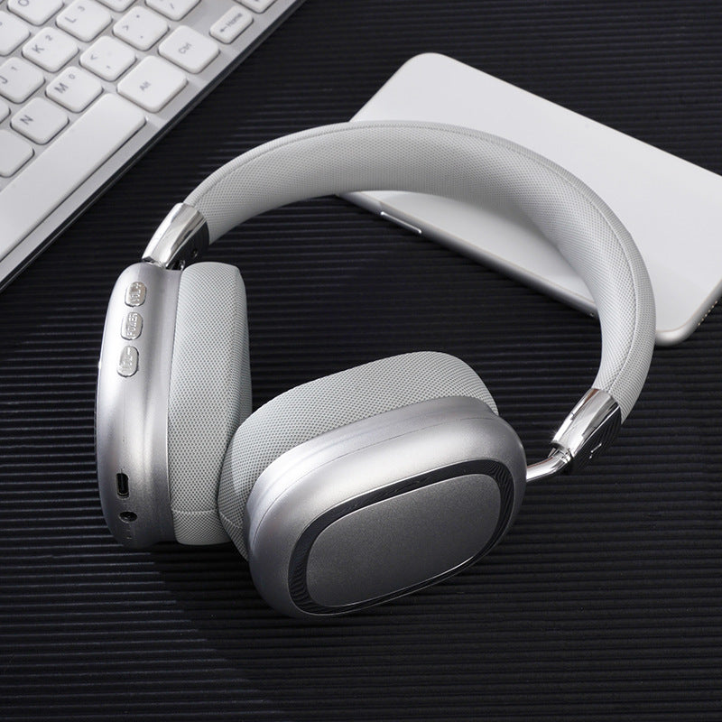 White headphones on a dark surface with a keyboard and white device in the background
