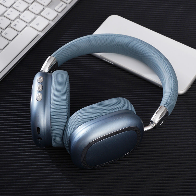 Blue headphones on a dark surface with a keyboard and mouse in the background