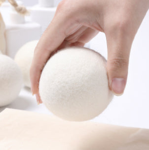 Hand holding a white round object against a neutral background