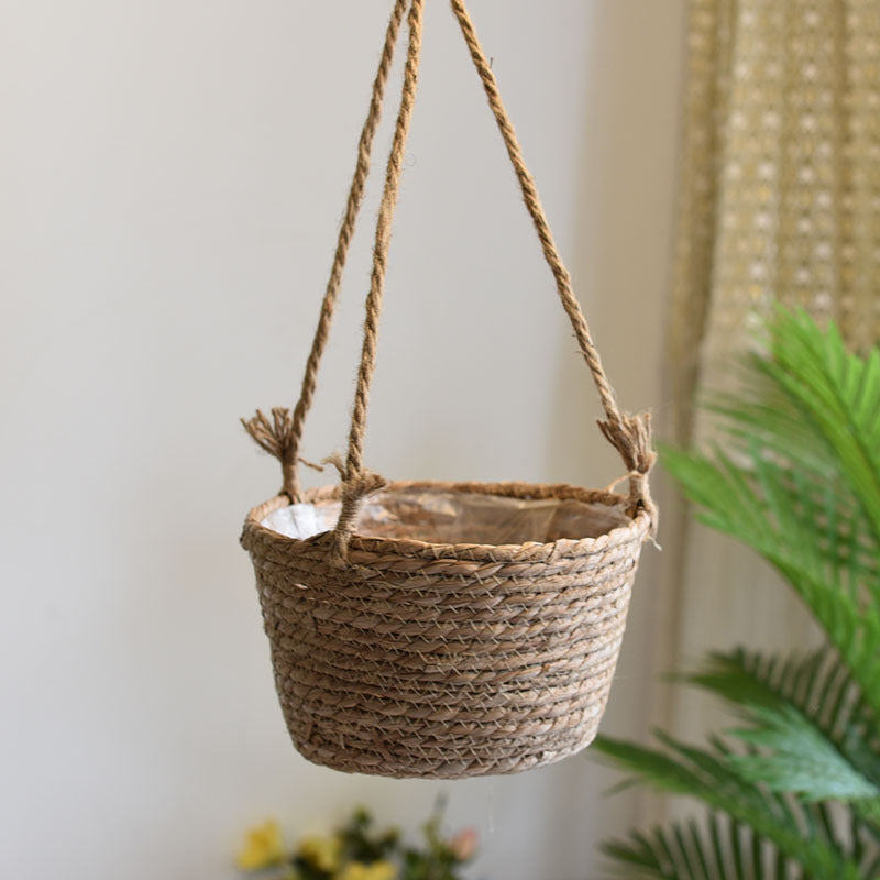 Woven hanging plant pot with rope details against a neutral background