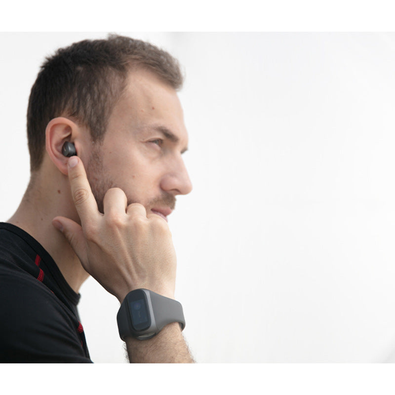 Man wearing a black smartwatch and wireless earbud on a white background