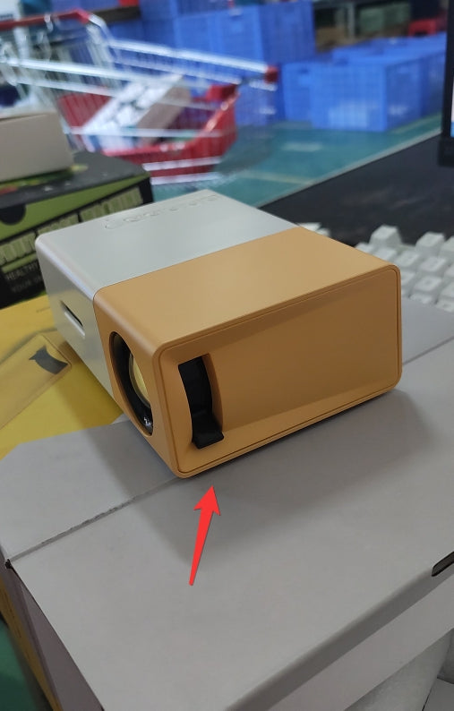 Small rectangular device with a yellow casing on a surface, with a red arrow pointing to it.