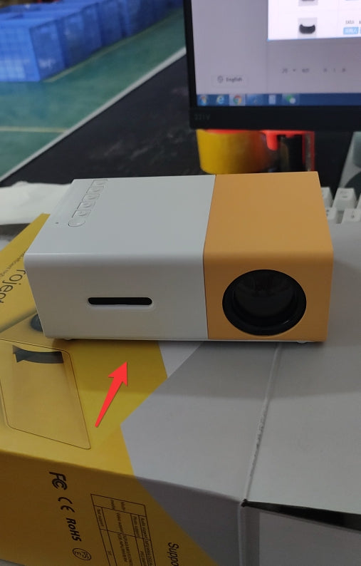 Small white and orange electronic device on a box with a red arrow pointing to it.