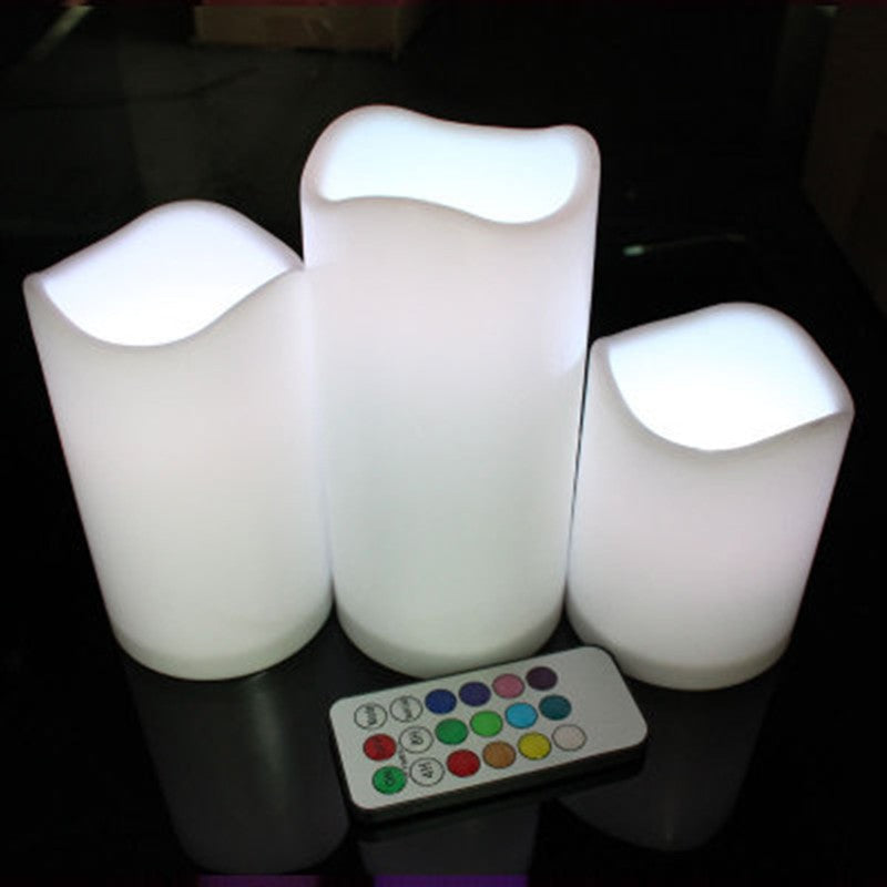 Three LED candles with a remote control on a dark surface