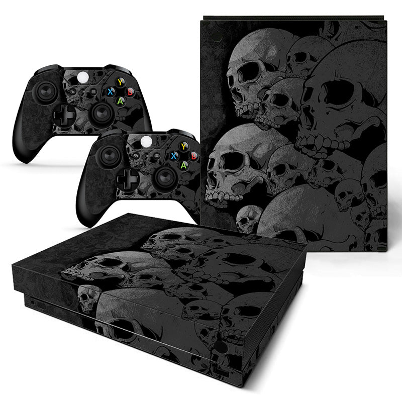 Gaming console and controllers with skull-themed skin on a white background
